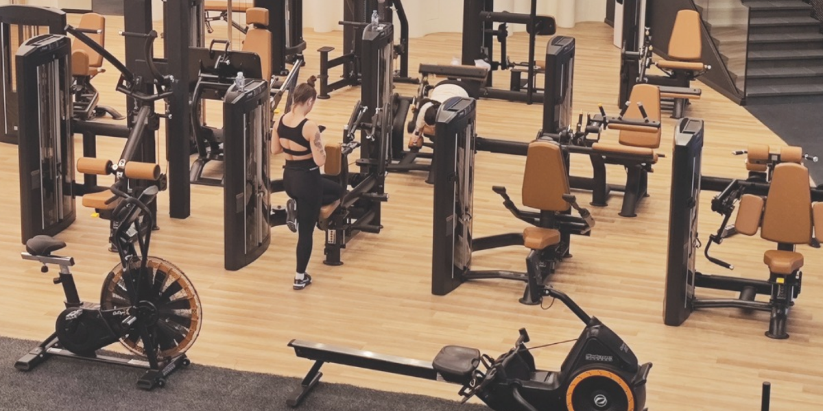 Modern fitness facility with wood-look flooring, strength training equipment, and cardio machines