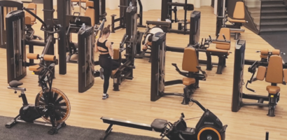 Modern fitness facility with wood-look flooring, strength training equipment, and cardio machines